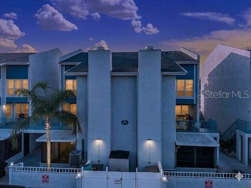 An exterior view of a multi-story townhouse building at dusk with a palm tree — 337 REX PLACE UNIT A, MADEIRA BEACH, FL
