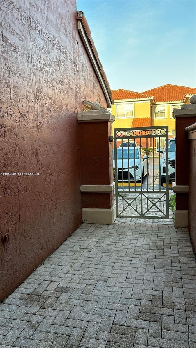 A narrow paved walkway leads to a metal gate between two stucco walls — 11479 NW 60th Ter # 373, Doral FL 33178, DORAL, FL