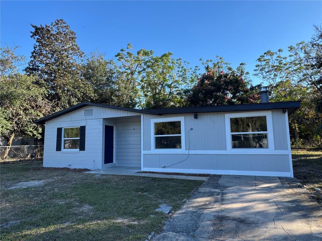 A single-story gray concrete block house with a recessed entryway and a side yard — 7224 VALIANT COURT, ORLANDO, FL