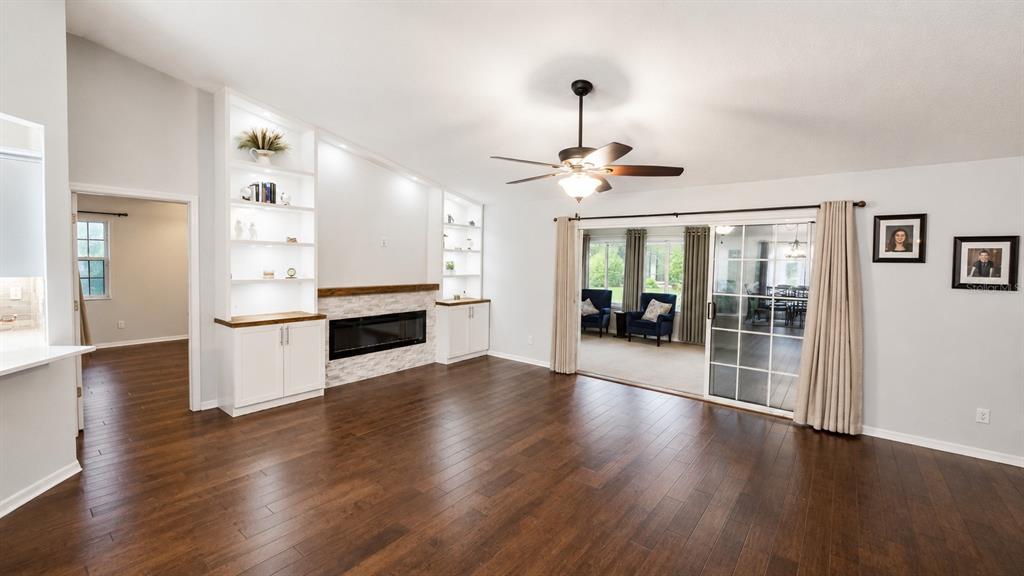 A living room features dark wood floors, a stone fireplace, built-in shelving, and sliding glass doors — 6441 SILVER OAKS DRIVE, ZEPHYRHILLS, FL
