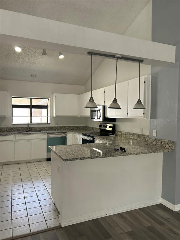A kitchen features white cabinets, granite countertops, a tiled floor, and three hanging pendant lights — 5106 STONEHURST ROAD, TAMPA, FL