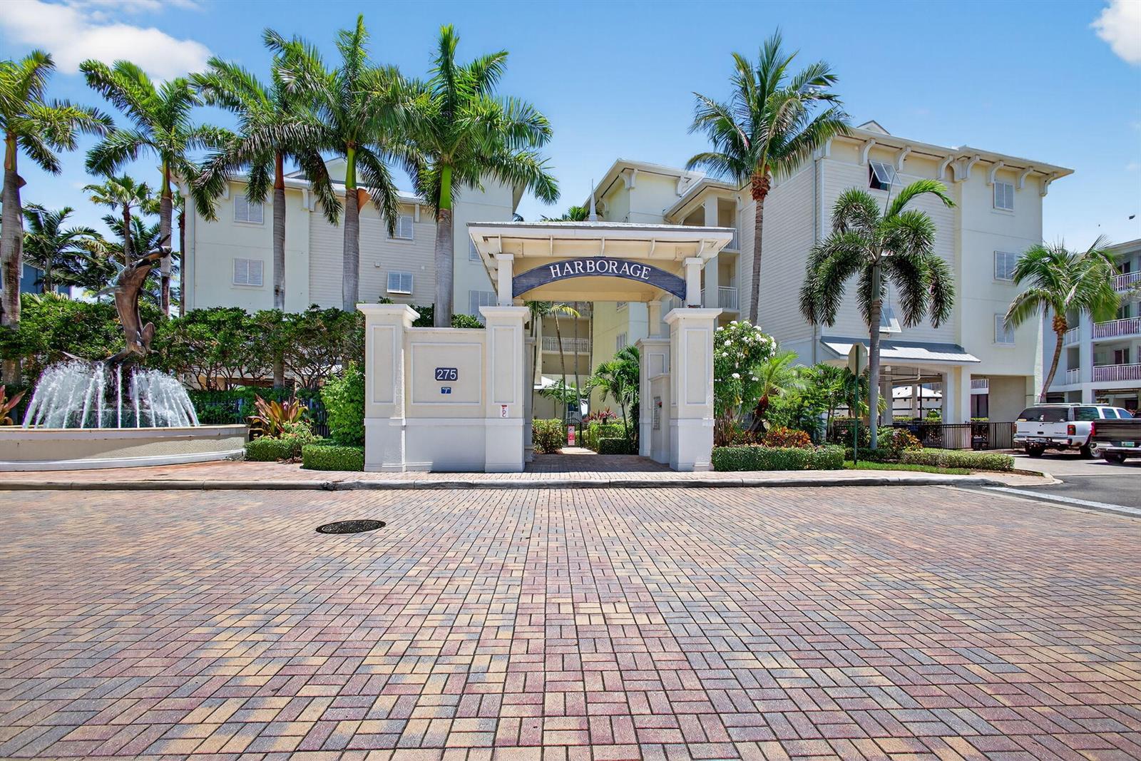 The entrance to a residential complex features a brick driveway, palm trees, and a fountain — 275 NW Flagler Avenue # 204, Stuart FL 34994, STUART, FL