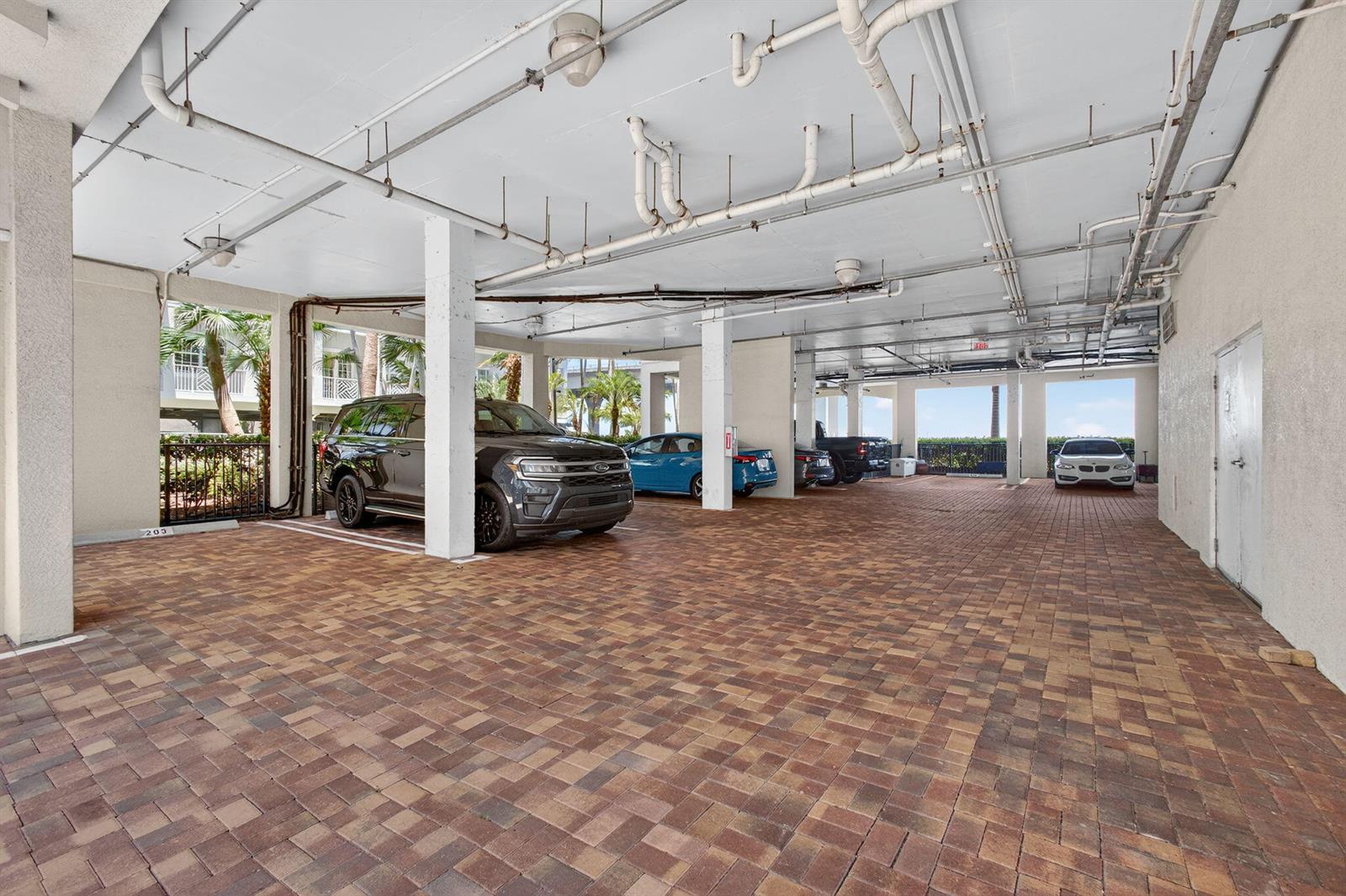A covered parking garage with brick pavers, concrete pillars, and exposed overhead pipes — 275 NW Flagler Avenue # 204, Stuart FL 34994, STUART, FL