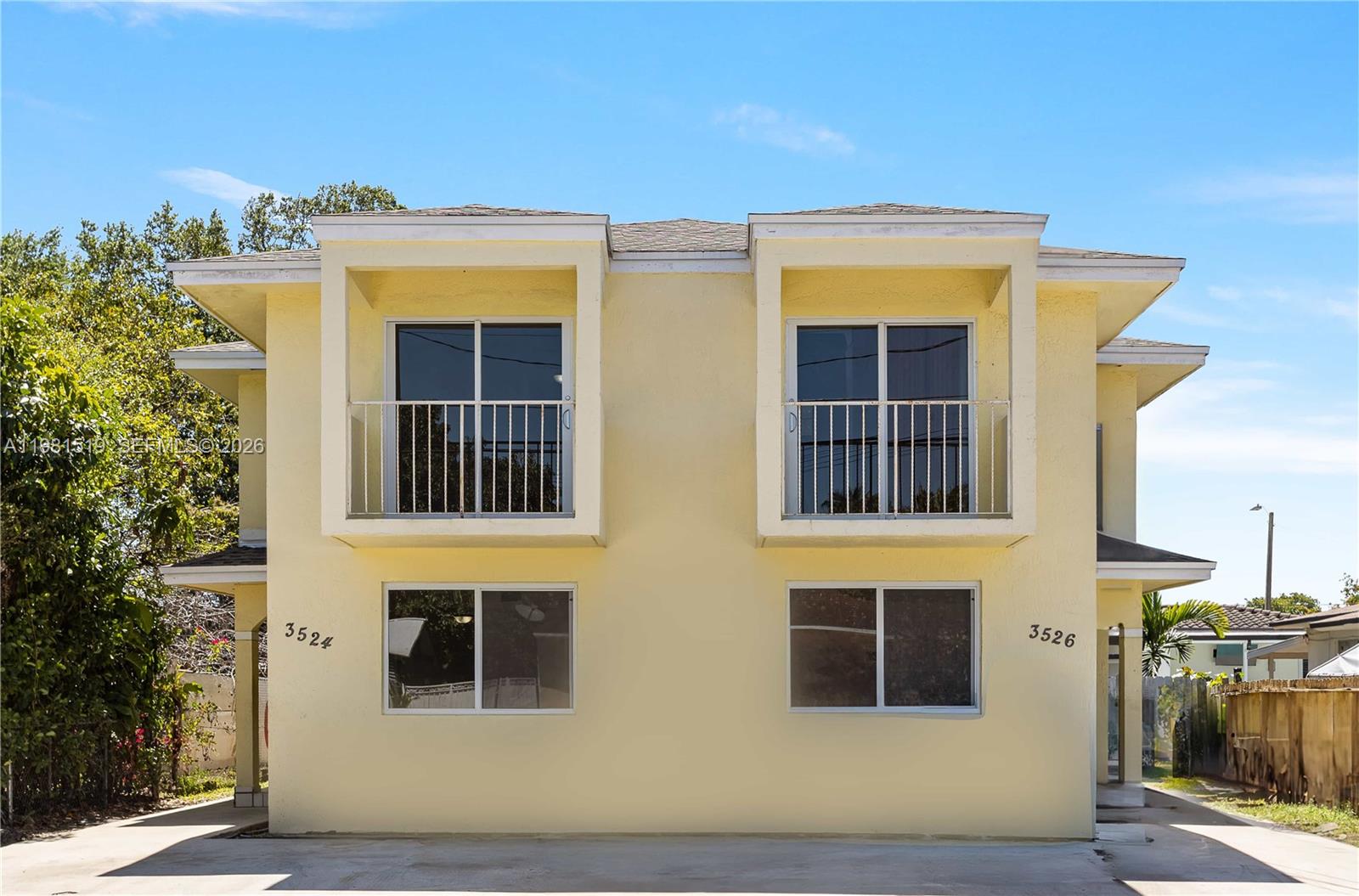 A two-story yellow duplex building features two upper-level balconies and ground-floor windows — 3524 NW 4th Ter, Miami FL 33125, MIAMI, FL