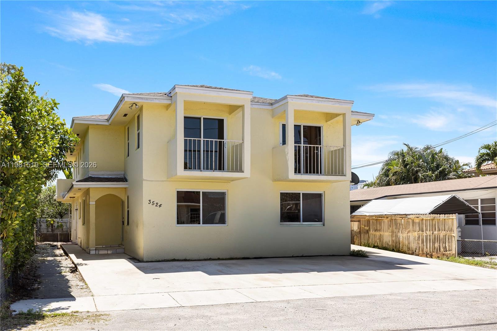 A two-story yellow stucco building features two upper-level balconies and a concrete driveway — 3524 NW 4th Ter, Miami FL 33125, MIAMI, FL