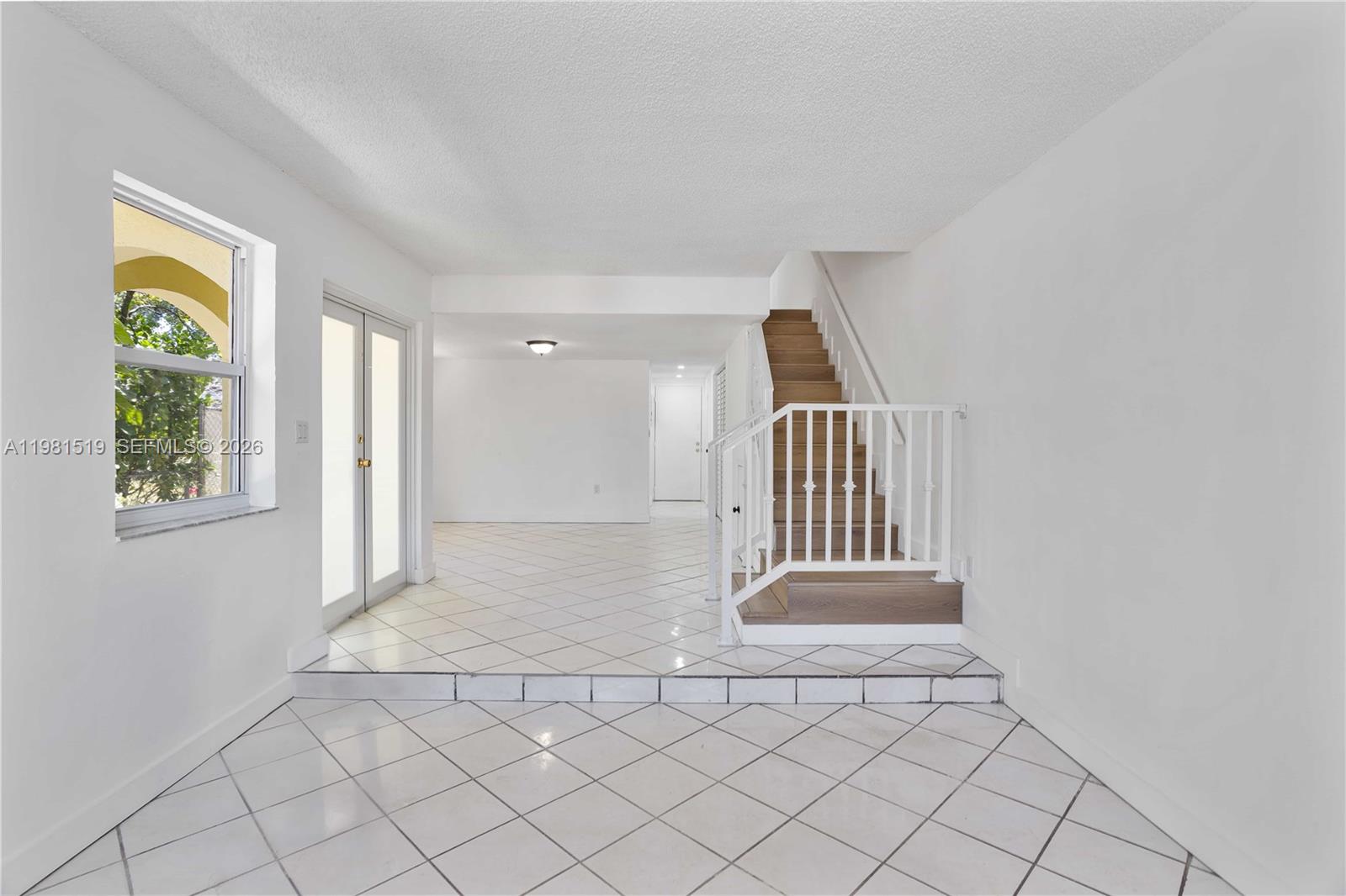 A sunken living area with white tile floors leads to a staircase with wooden treads — 3524 NW 4th Ter, Miami FL 33125, MIAMI, FL