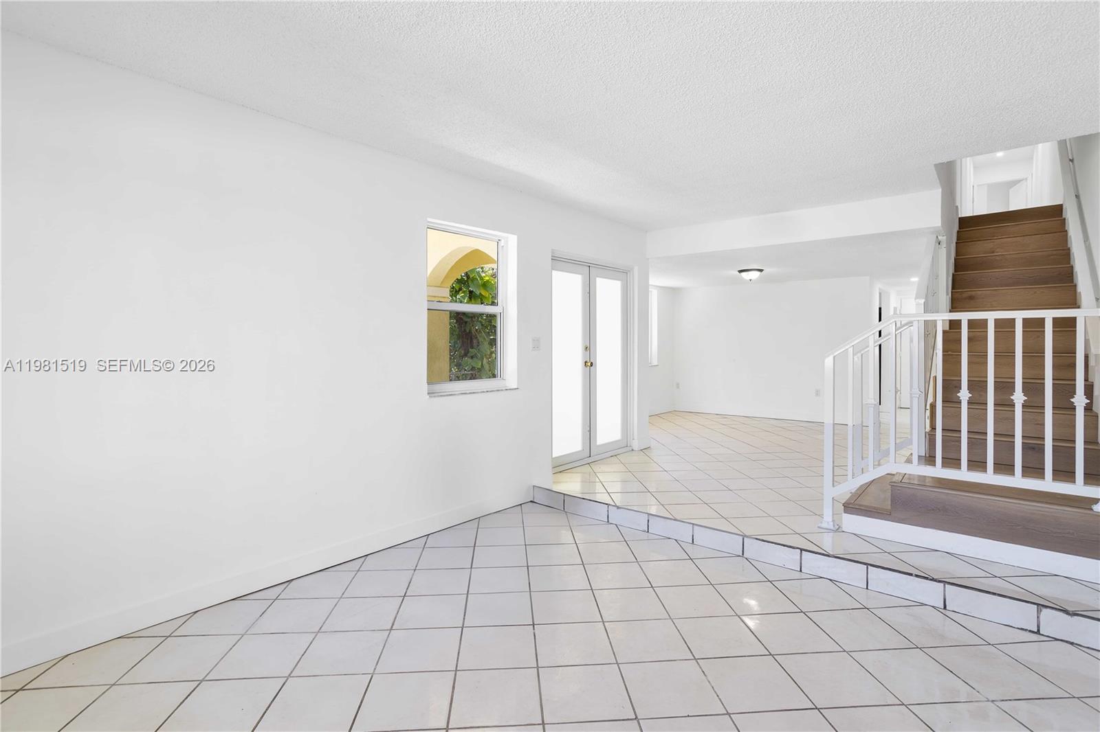 A living area features white tile flooring, a sunken section, and a wooden staircase — 3524 NW 4th Ter, Miami FL 33125, MIAMI, FL