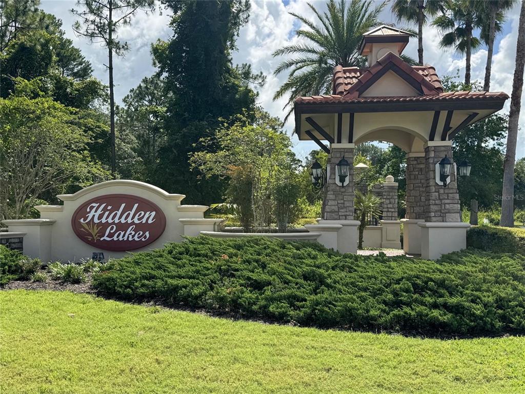 A stone and stucco entrance monument for a community named Hidden Lakes with landscaping — 53 AUBERRY DRIVE, PALM COAST, FL