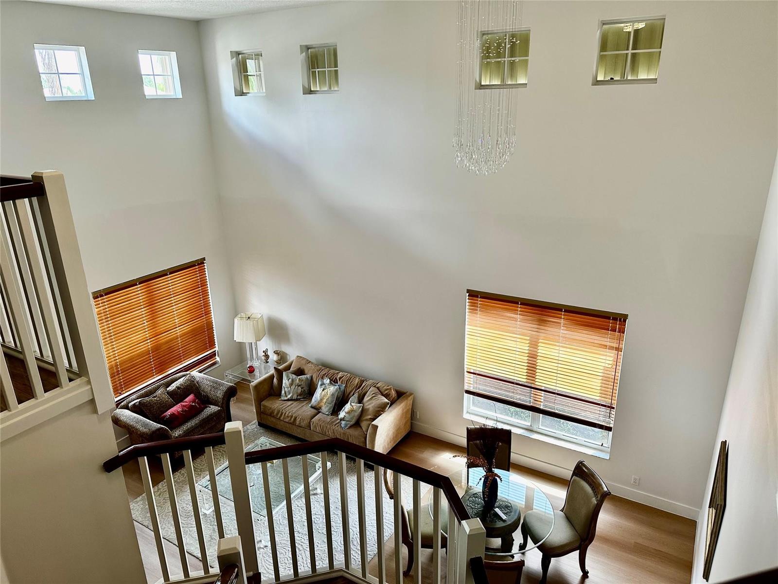 A high-angle view of a two-story living and dining area with tall white walls — 8564 Via Giardino, Boca Raton FL 33433, BOCA RATON, FL