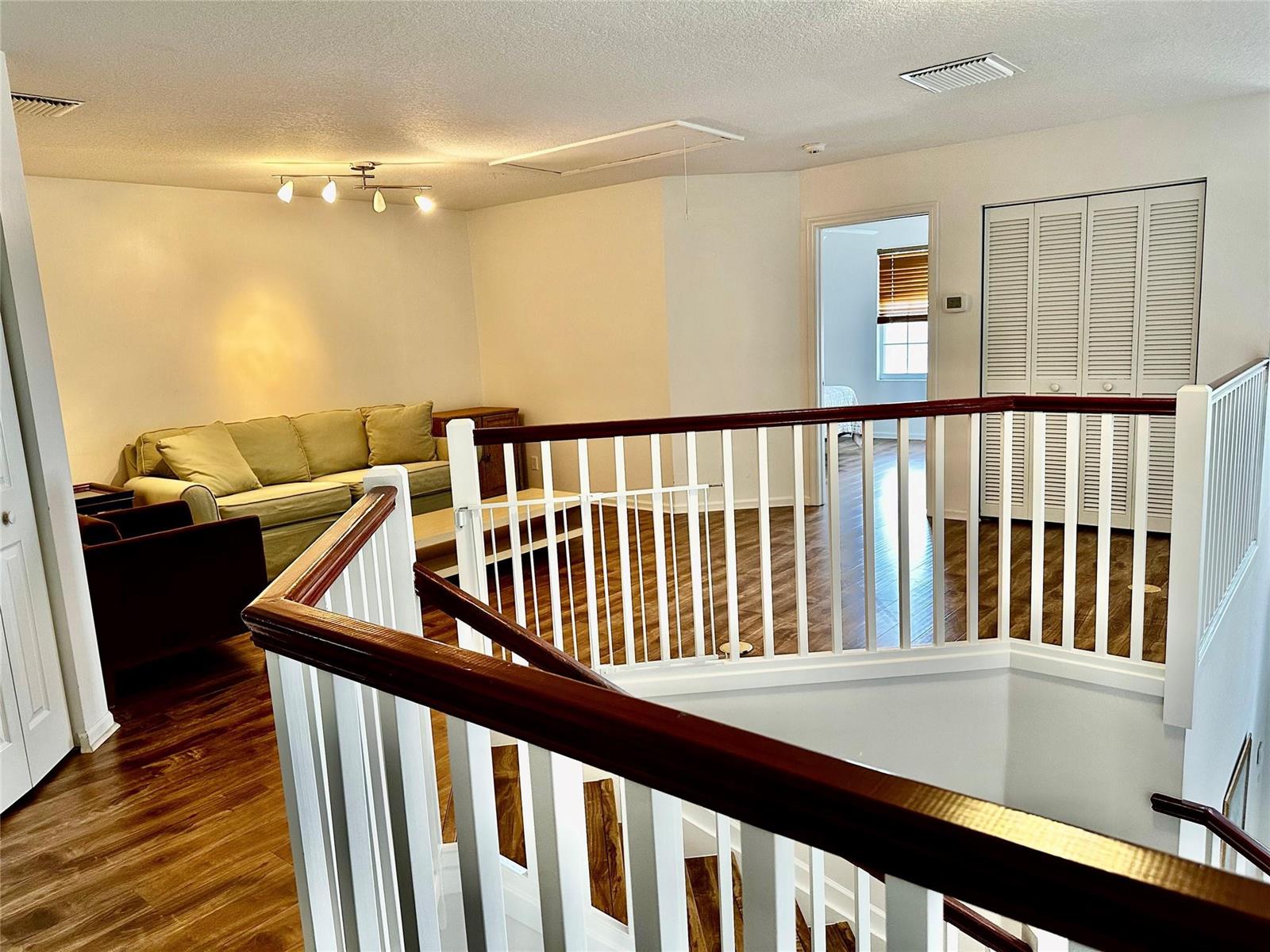 A carpeted loft area features wood-look flooring, a sofa, and a white wooden staircase railing — 8564 Via Giardino, Boca Raton FL 33433, BOCA RATON, FL