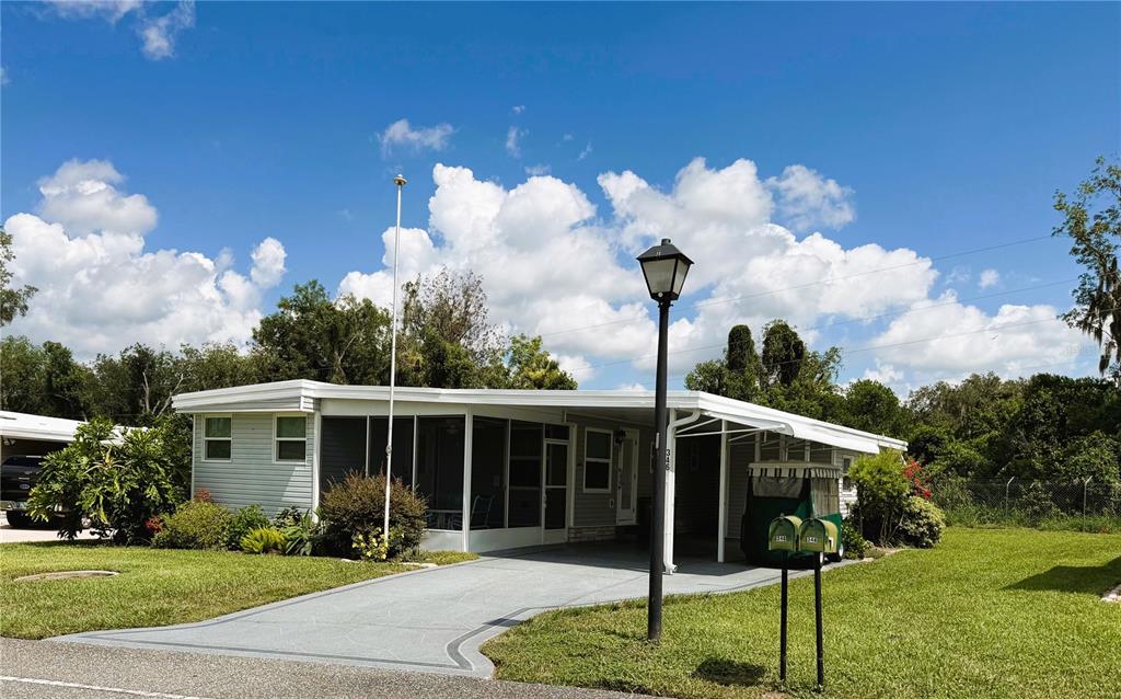 A single-story manufactured home features a screened porch, a carport, and a paved driveway — 346 PALO VERDE DRIVE, LEESBURG, FL
