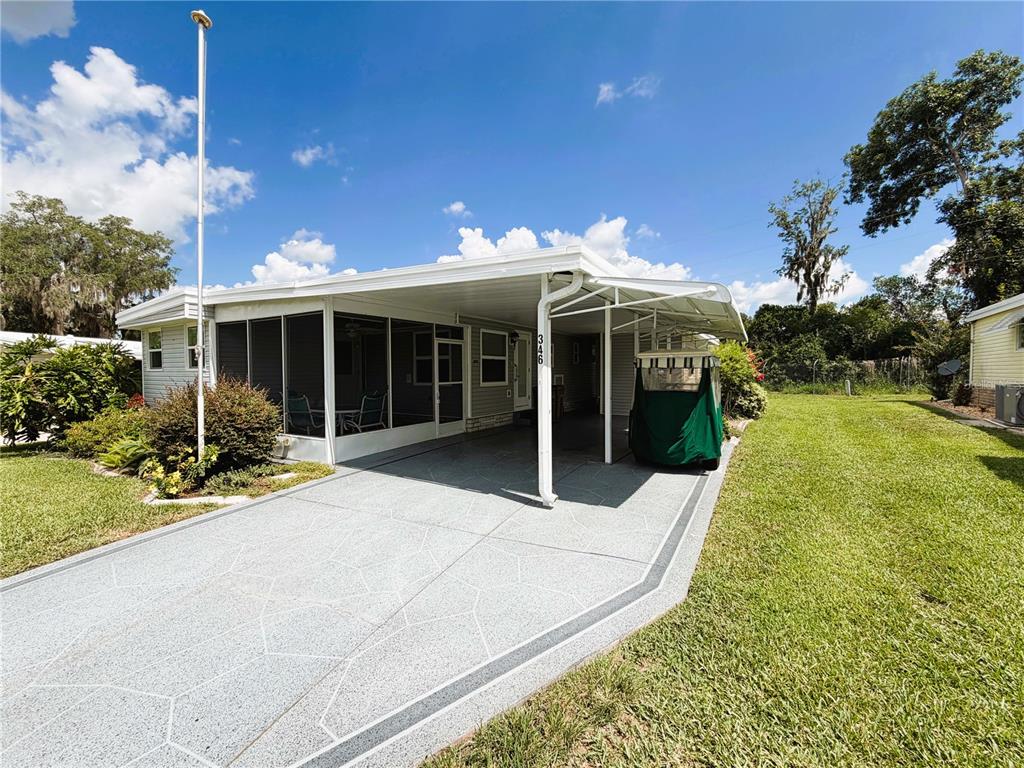 A single-story home features a screened-in porch, a covered carport, and a concrete driveway — 346 PALO VERDE DRIVE, LEESBURG, FL