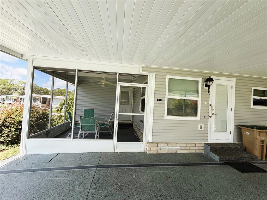 A covered carport leads to a screened-in porch and a white front door — 346 PALO VERDE DRIVE, LEESBURG, FL