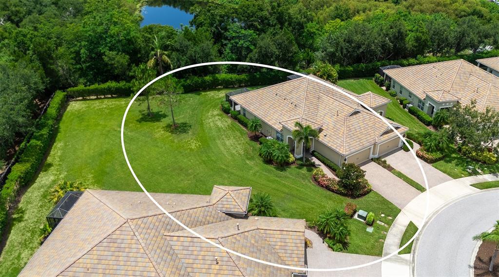 An aerial view shows a tan house with a tiled roof and a large lawn — 4866 MAYMONT PARK CIRCLE, BRADENTON, FL