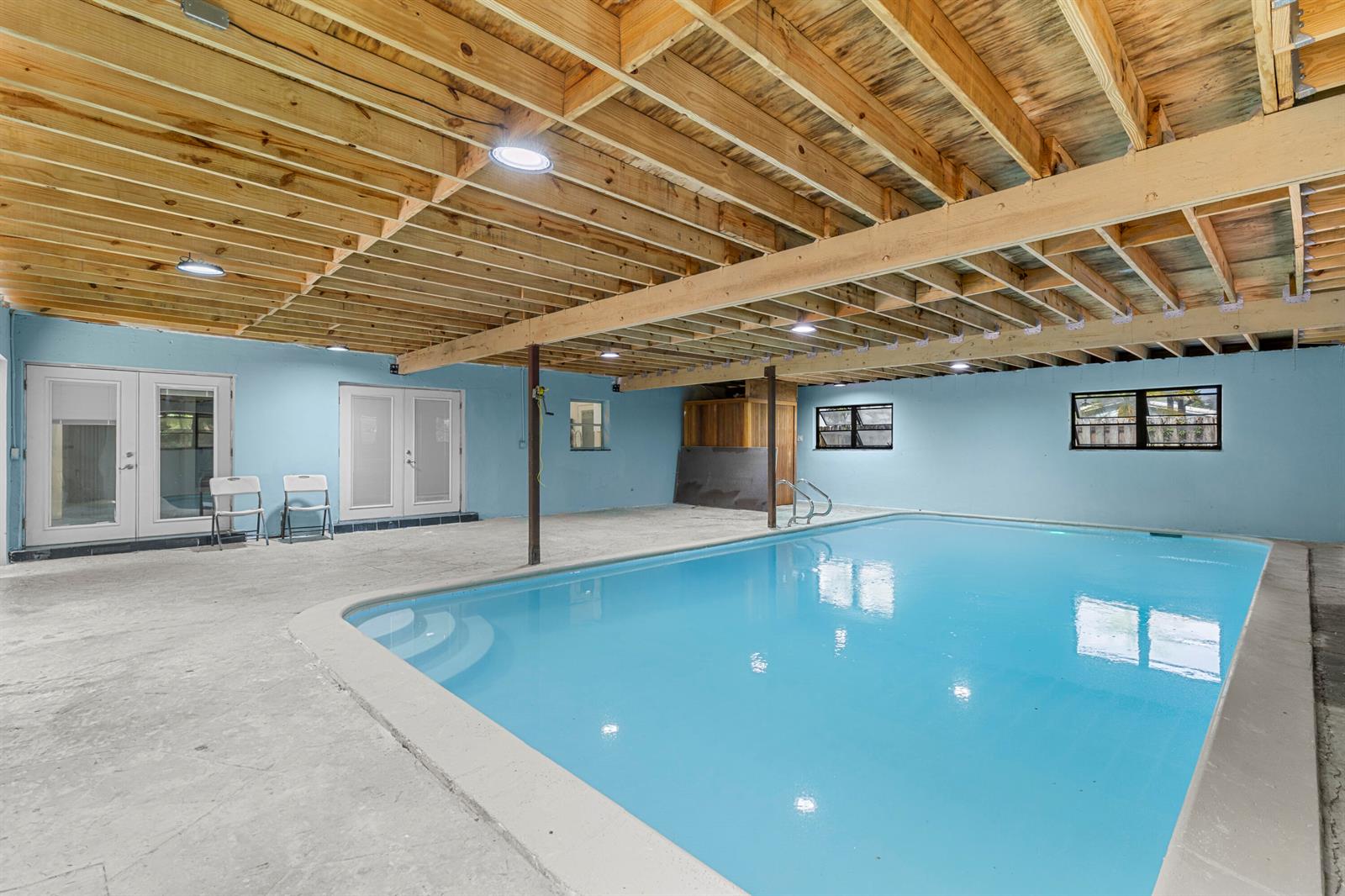 An indoor swimming pool room with exposed wooden ceiling joists and light blue walls — 3313 SW 19th Street, Fort Lauderdale FL 33312, FORT LAUDERDALE, FL