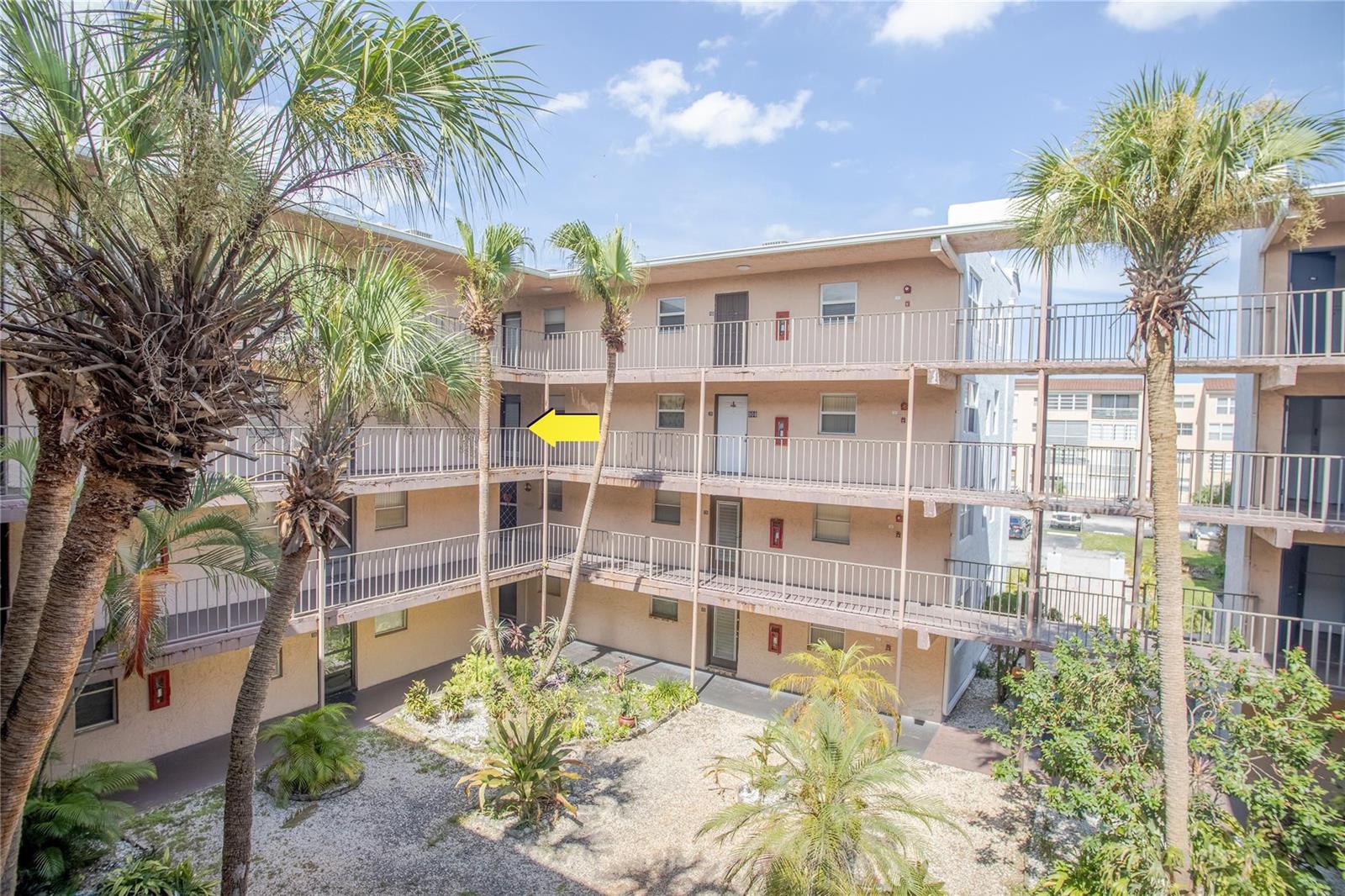 An exterior view of a multi-story apartment building with open walkways and a central courtyard — 2850 Somerset Drive # 307L, Lauderdale Lakes FL 33311, LAUDERDALE LAKES, FL
