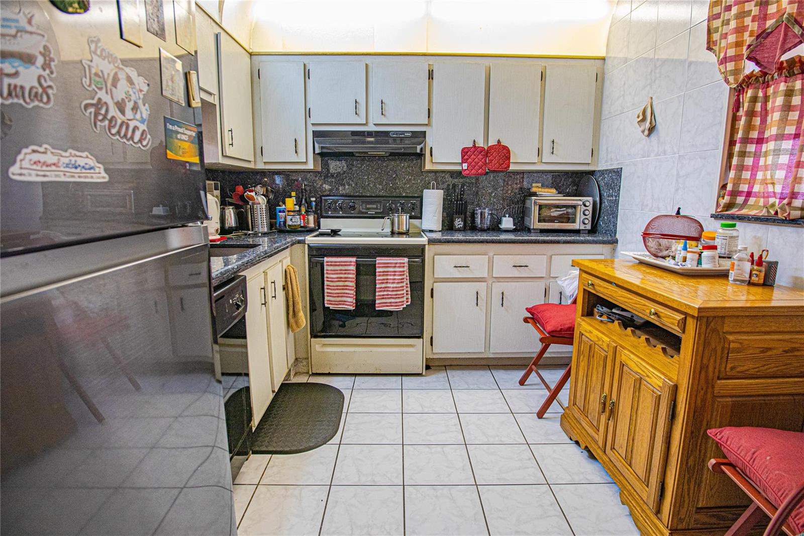 A kitchen features white cabinets, dark granite countertops, a black stove, and white tile flooring — 2850 Somerset Drive # 307L, Lauderdale Lakes FL 33311, LAUDERDALE LAKES, FL