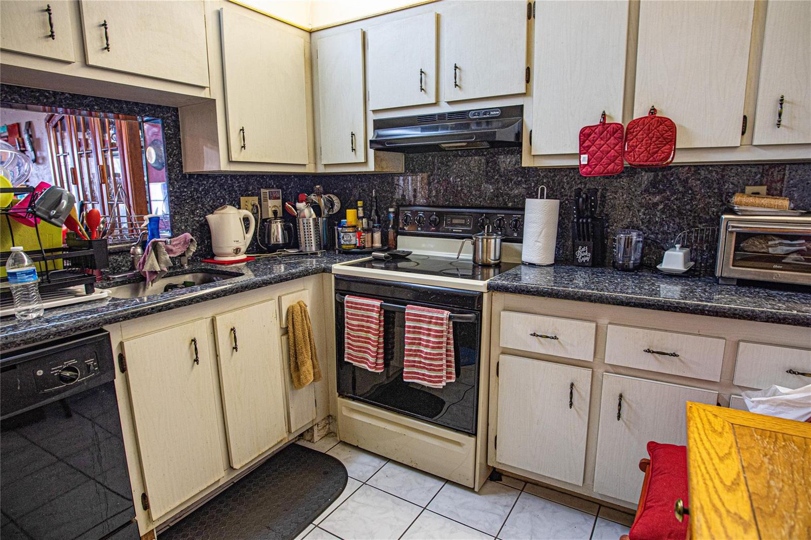 A kitchen features white cabinets, dark granite countertops, a black stove, and tiled flooring — 2850 Somerset Drive # 307L, Lauderdale Lakes FL 33311, LAUDERDALE LAKES, FL