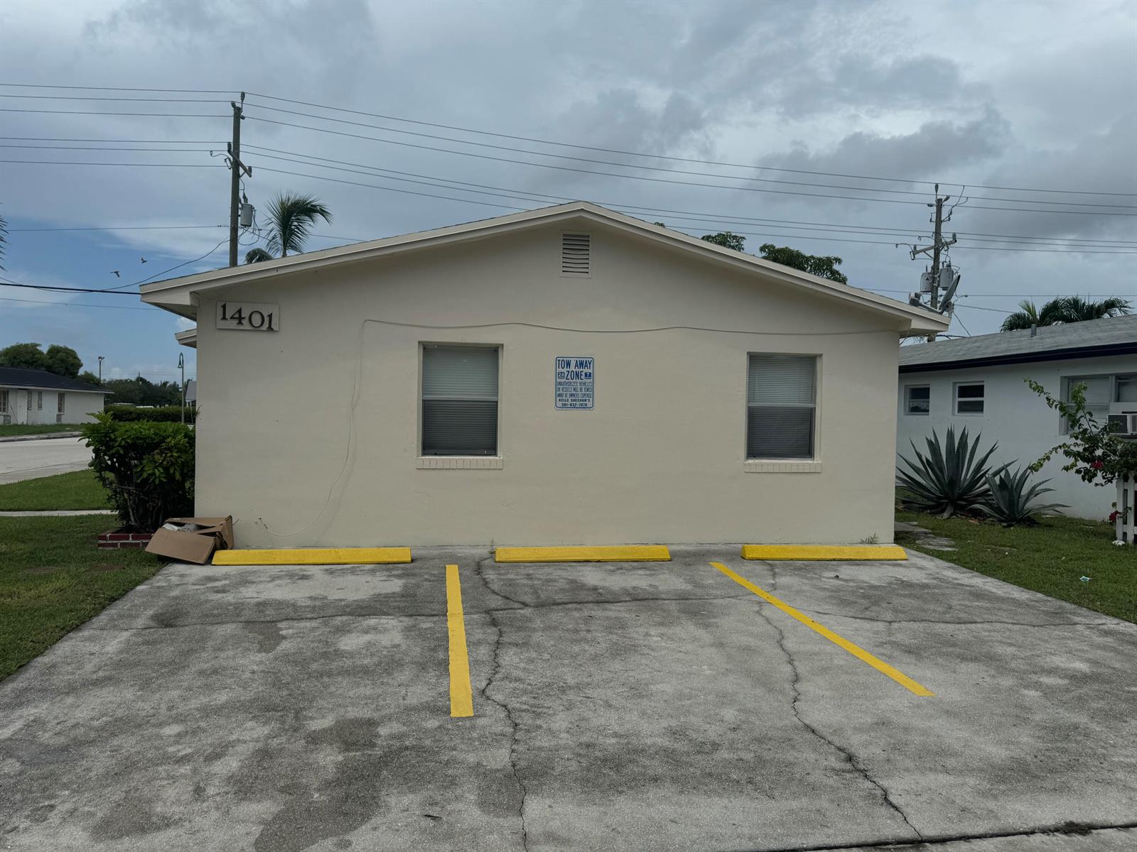 A single-story building with a beige exterior, two windows, and three marked parking spaces — 1401 N J Street # A, FL 33460, FL