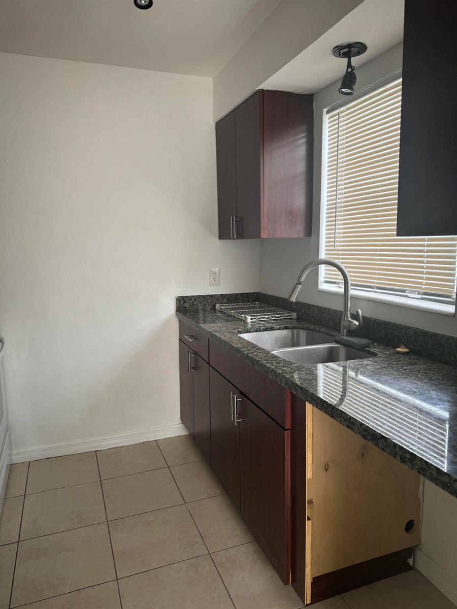 A kitchen features dark wood cabinets, granite countertops, a double sink, and tile flooring — 1401 N J Street # A, FL 33460, FL