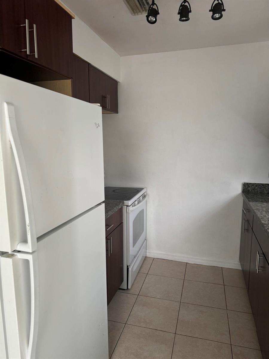 A kitchen features dark wood cabinets, a white refrigerator, a white stove, and tile flooring — 1401 N J Street # A, FL 33460, FL