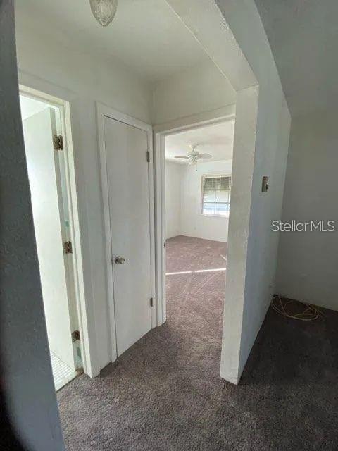 A hallway with a closed door leads to a carpeted bedroom with a ceiling fan — 4018 6TH STREET S UNIT 10, ST PETERSBURG, FL
