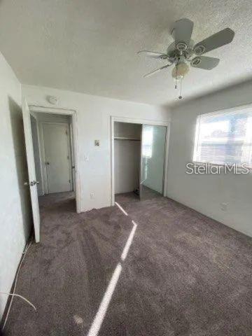 A bedroom with gray carpet, a ceiling fan, a closet with mirrored doors, and a doorway — 4018 6TH STREET S UNIT 10, ST PETERSBURG, FL