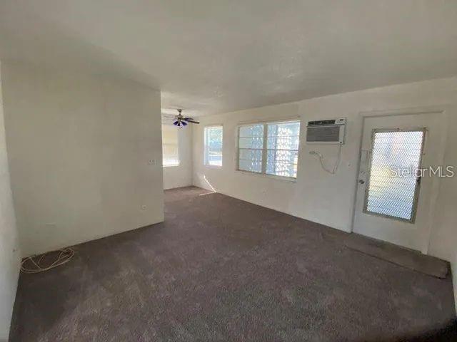 An empty living room features gray carpeting, white walls, a ceiling fan, and a screen door — 4018 6TH STREET S UNIT 10, ST PETERSBURG, FL