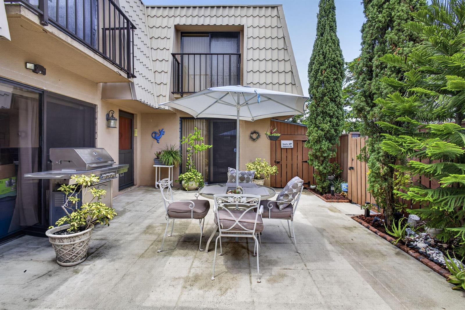 A patio features a dining set with an umbrella, a grill, and potted plants — 5034 50th Way, West Palm Beach FL 33409, WEST PALM BEACH, FL