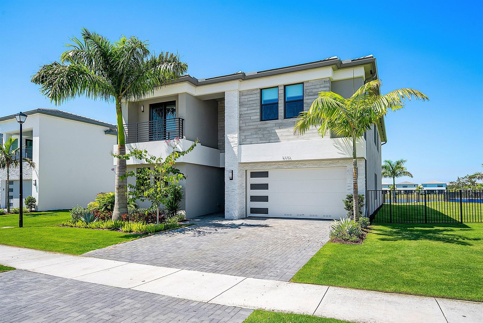 A two-story modern house features a paved driveway, palm trees, and a white garage door — 9370 Sunflower Meadow Road, Boca Raton FL 33434, BOCA RATON, FL