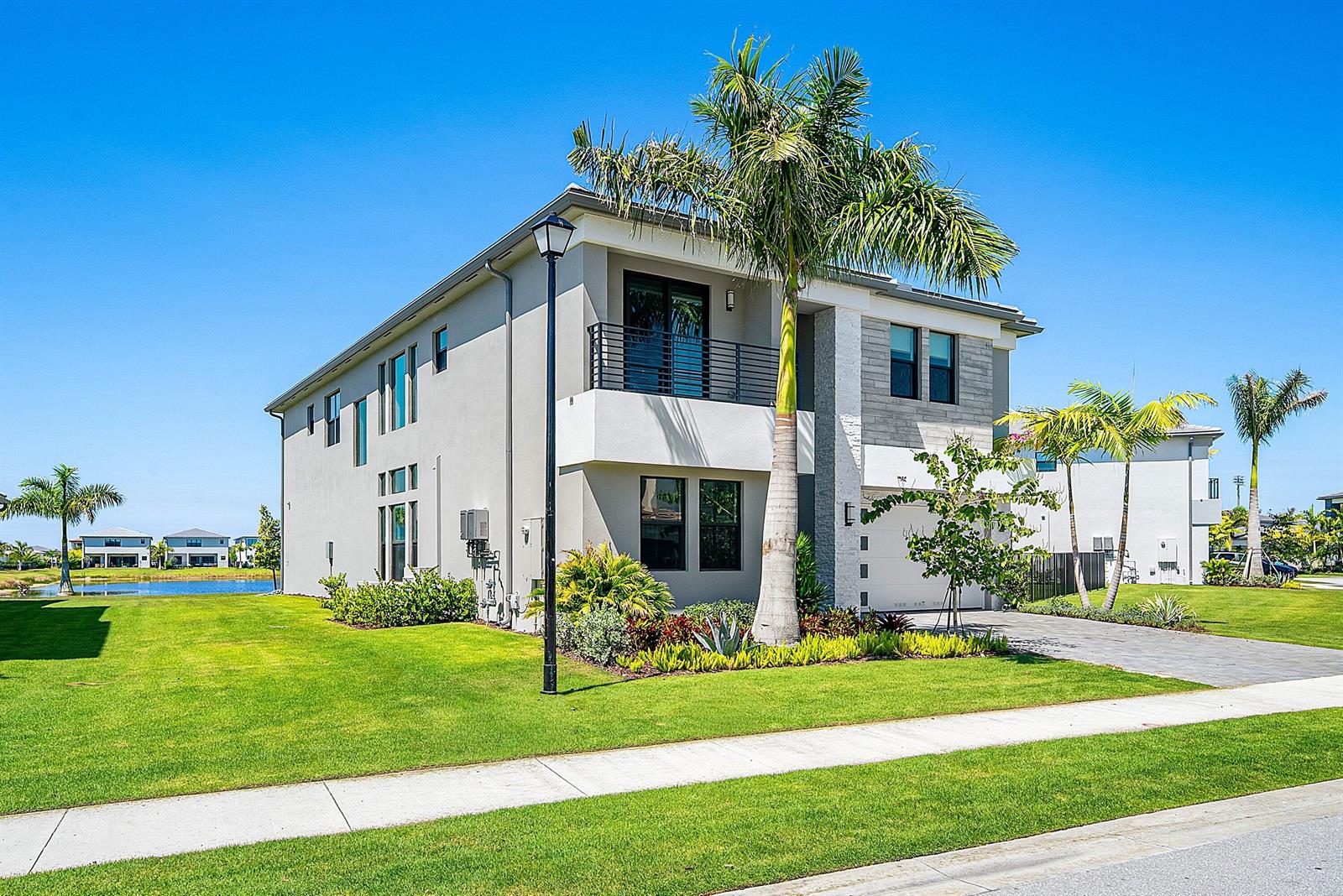 A two-story modern house with a palm tree, balcony, and driveway under a blue sky — 9370 Sunflower Meadow Road, Boca Raton FL 33434, BOCA RATON, FL