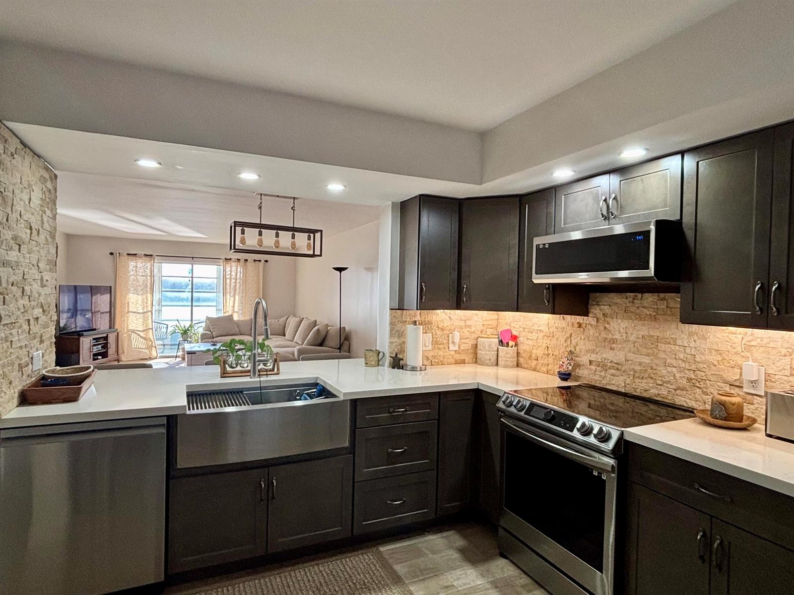A kitchen with dark cabinets, white countertops, a farmhouse sink, and a stone backsplash — 1501 SW 134th Way Unit 304, Pembroke Pines FL 33027, PEMBROKE PINES, FL