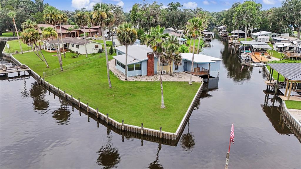 A single-story house with a metal roof and carport sits on a grassy, fenced lot — 56440 WATER OAK ROAD, ASTOR, FL