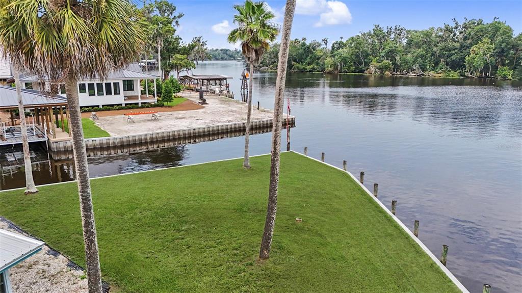A light blue house with a metal roof and a concrete driveway sits near water — 56440 WATER OAK ROAD, ASTOR, FL