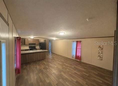 An open-concept living area features wood-look flooring, a kitchen island, and light-colored walls — 10350 SE 127TH LANE, BELLEVIEW, FL