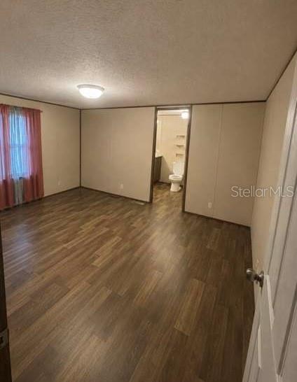 A bedroom with wood-look flooring and a doorway leading to an attached bathroom — 10350 SE 127TH LANE, BELLEVIEW, FL