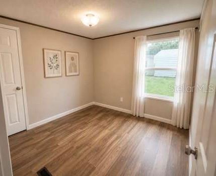 A bedroom with light-colored walls, wood-look flooring, a window with curtains, and two framed pictures — 10350 SE 127TH LANE, BELLEVIEW, FL