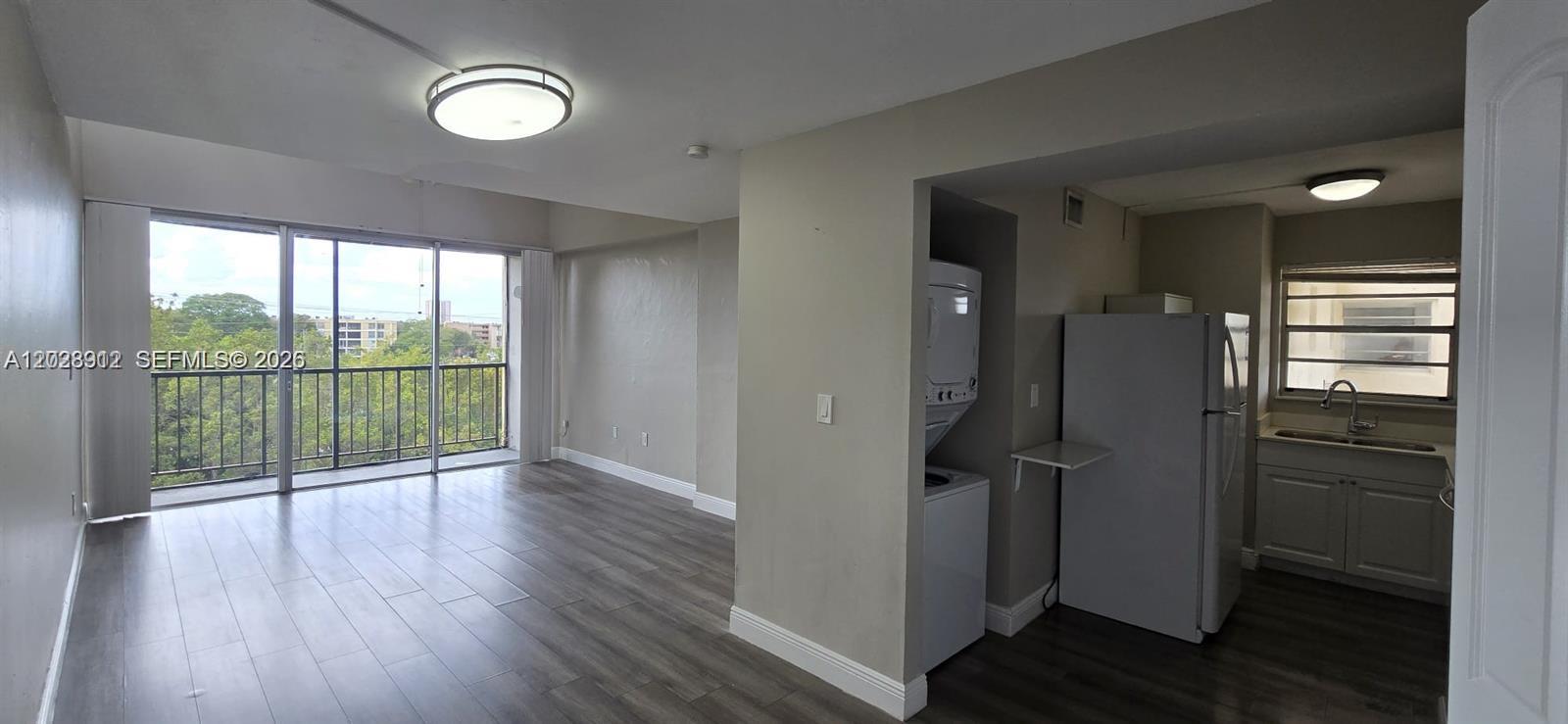 An open-concept living area features wood-look flooring, a sliding glass door, and an adjacent kitchen — 8870 Fontainebleau Blvd # 502, Miami FL 33172, MIAMI, FL