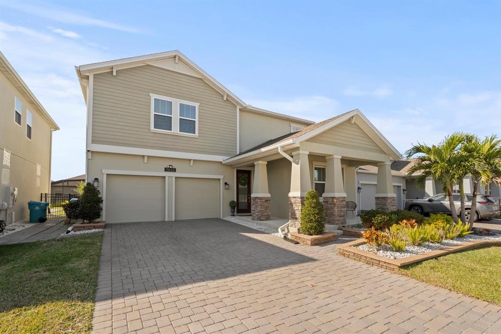 A two-story suburban house with a paved driveway, stone-accented porch, and tan siding — 11632 PARAGRAPH ROAD, ORLANDO, FL