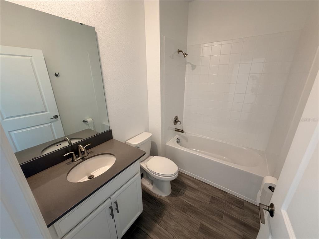 A bathroom features a white vanity with a dark countertop, a toilet, and a tub-shower — 11632 PARAGRAPH ROAD, ORLANDO, FL