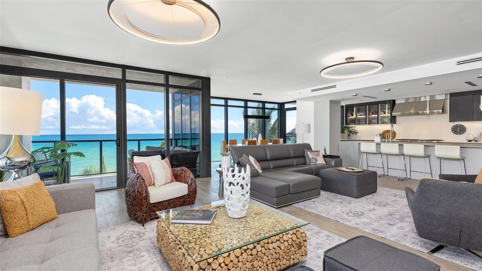 A modern living room and kitchen area features floor-to-ceiling windows with ocean views — 2205 S Surf Road # 4b, Hollywood FL 33019, HOLLYWOOD, FL
