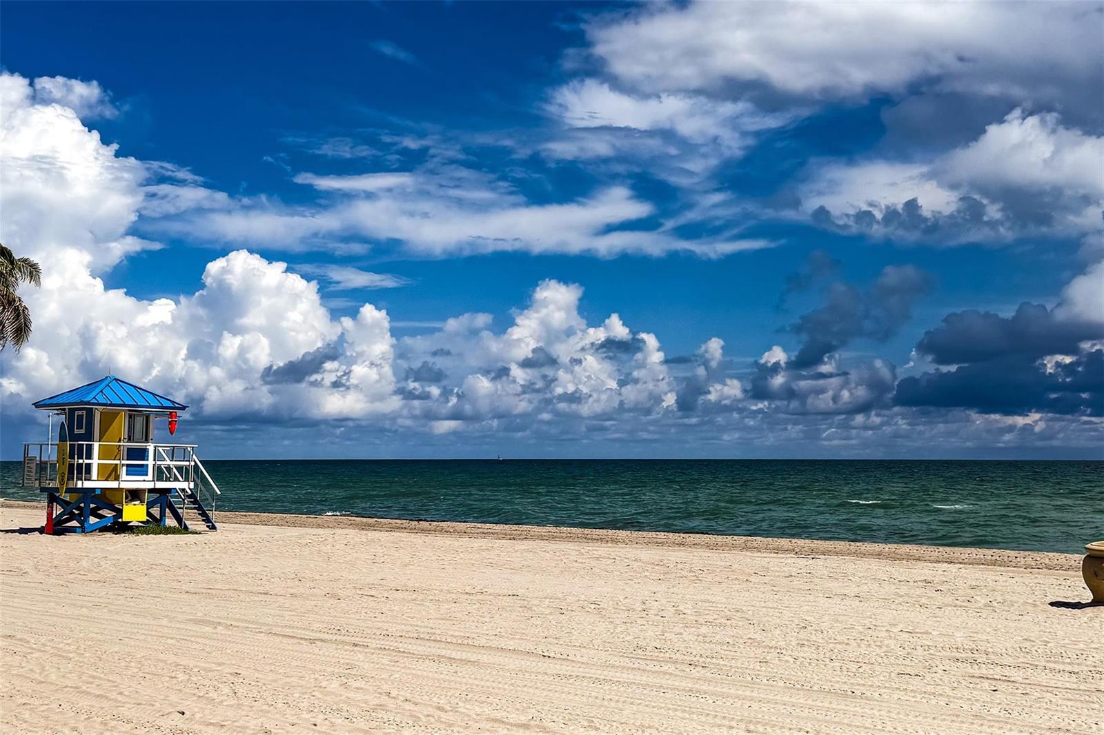 A colorful lifeguard tower stands on a sandy beach under a blue, cloudy sky — 2205 S Surf Road # 4b, Hollywood FL 33019, HOLLYWOOD, FL