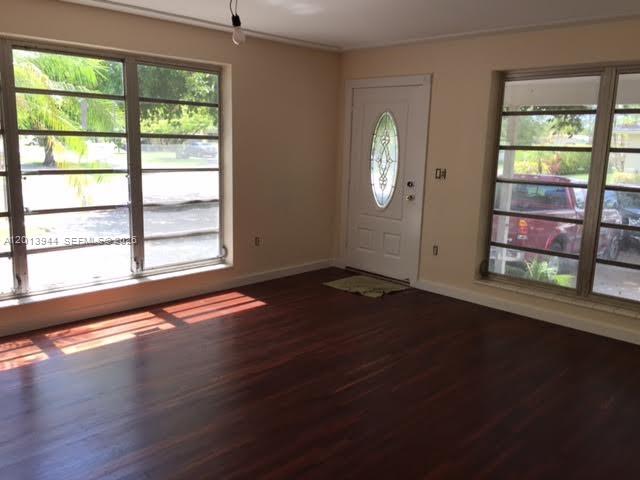 A room with dark wood floors, large windows, and a white front door with glass — 335 NE 114th St # 1, Miami FL 33161, MIAMI, FL
