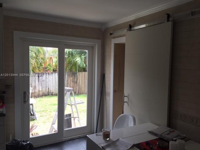 A room with a sliding glass door leading to a backyard and a sliding barn door — 335 NE 114th St # 1, Miami FL 33161, MIAMI, FL