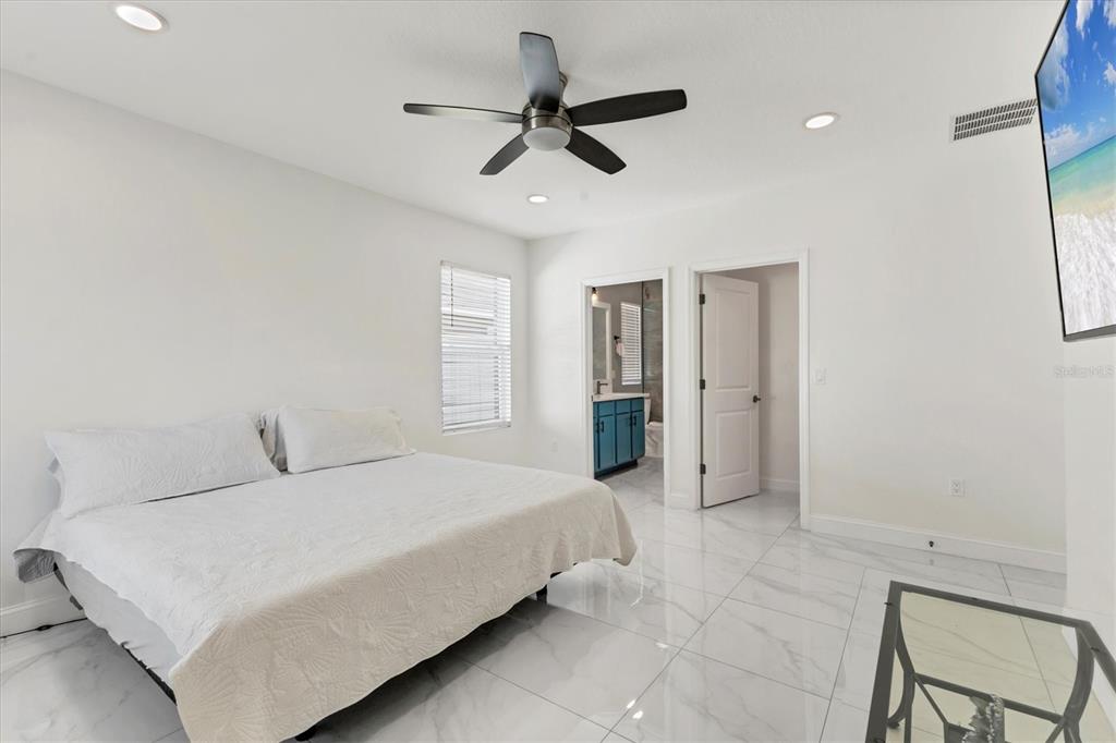 A bedroom features white walls, a ceiling fan, white tile flooring, and an attached bathroom — 177 TIERRA VERDE WAY, BRADENTON, FL