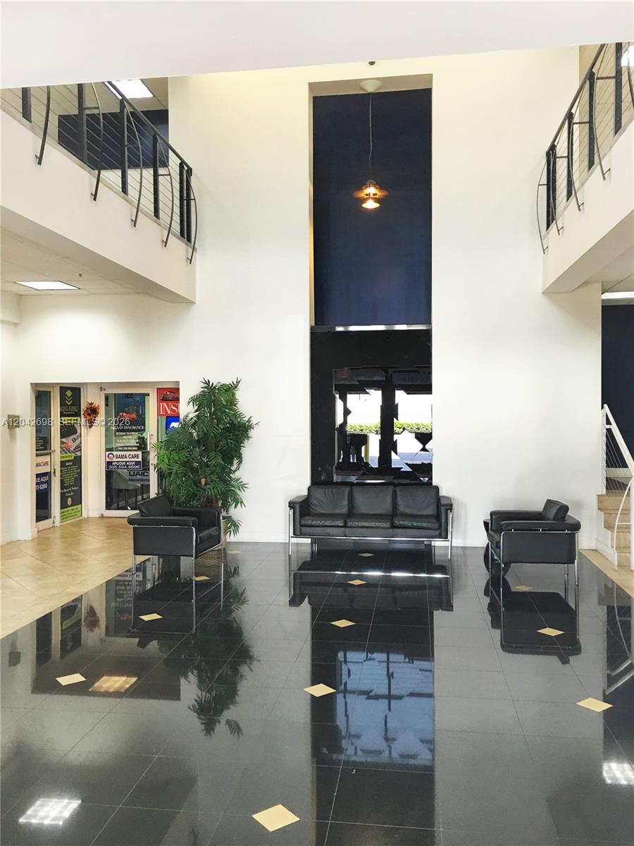 A modern office building lobby features a black tiled floor, black leather seating, and balconies — 7500 NW 25th St # 256, Miami FL 33122, MIAMI, FL