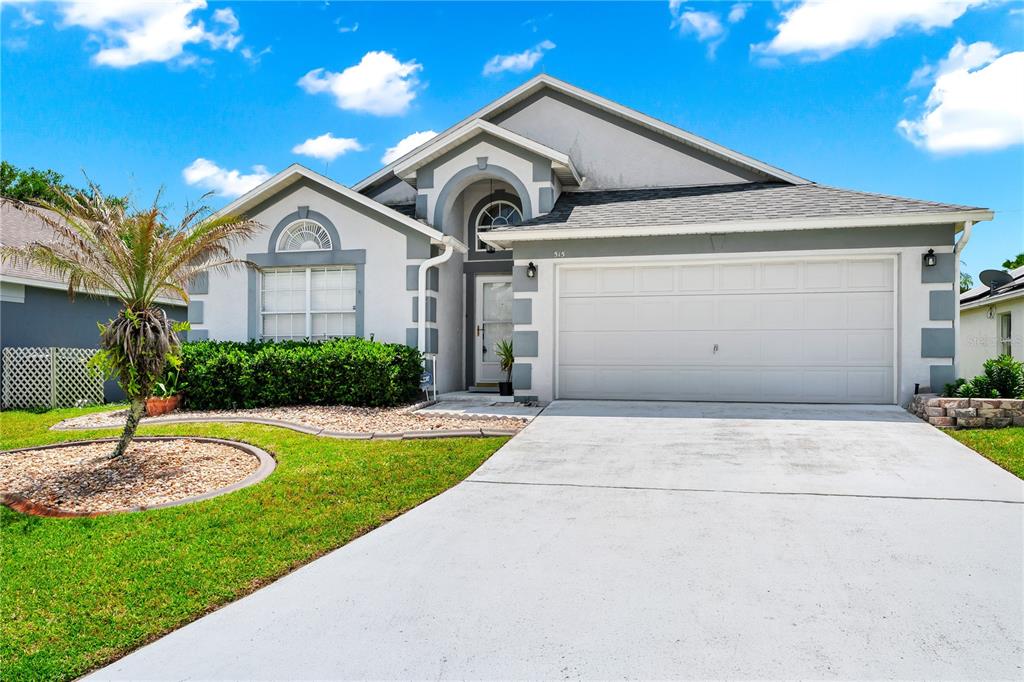 A single-story house with a white garage, gray trim, and a small palm tree — 515 LAKE DAVENPORT BOULEVARD, DAVENPORT, FL