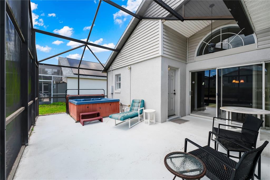 A screened-in patio features a hot tub, lounge chair, and outdoor seating on concrete flooring — 515 LAKE DAVENPORT BOULEVARD, DAVENPORT, FL