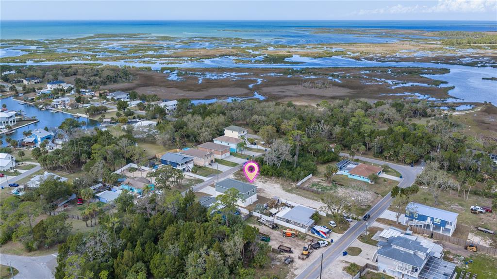 An aerial view shows a two-story house with a pin marker near a coastal marsh — 5056 OAK LEAF LANE, HERNANDO BEACH, FL