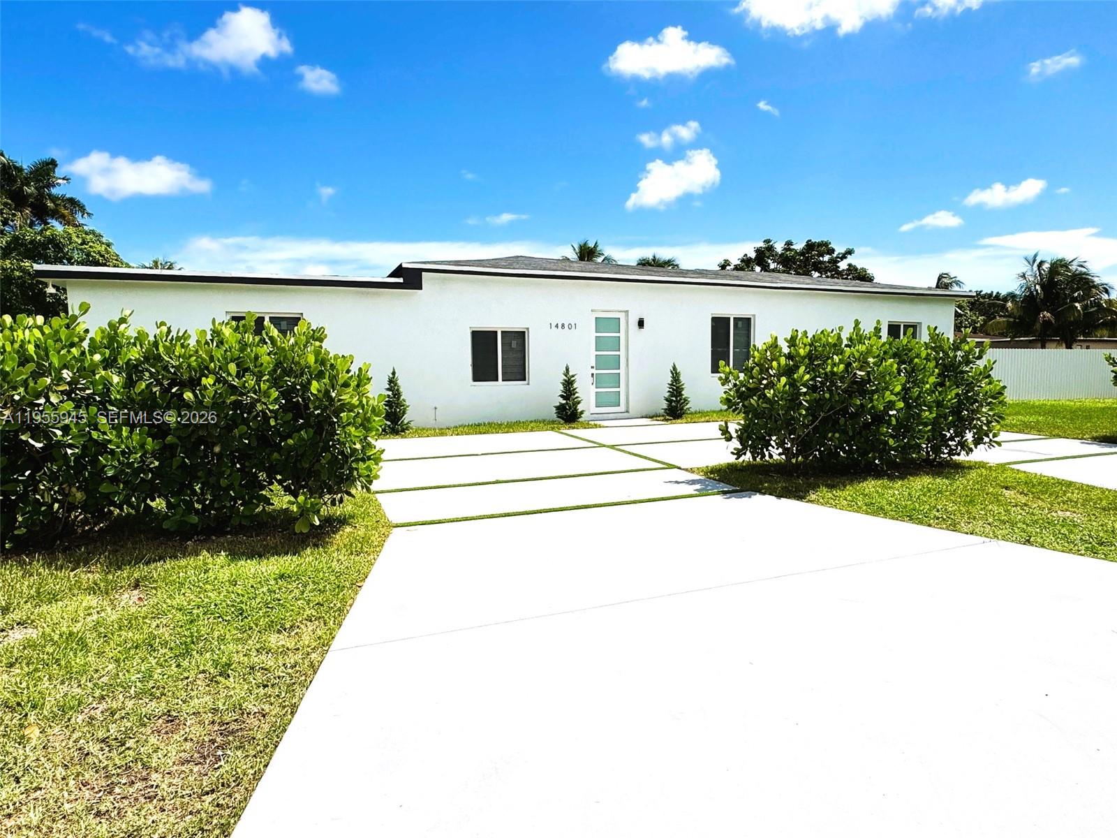 A white single-story house features a modern front door and a concrete driveway — 14801 NW 5th Ave, Miami FL 33168, MIAMI, FL